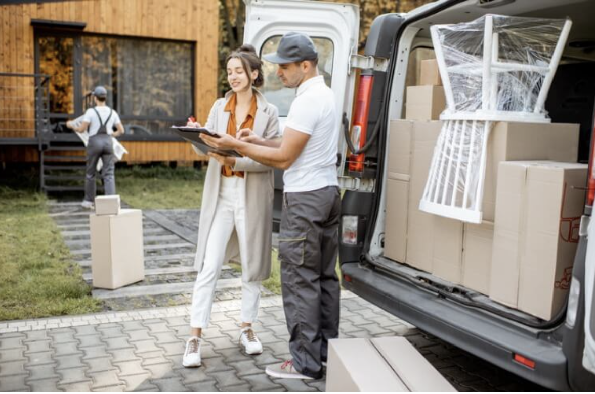 Client reviewing a moving checklist on a clipboard with a mover beside a loaded moving van